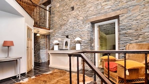 A rustic interior with stone walls, a wooden staircase, a leather rug, and wicker furniture. - Ardennic Farmhouse for Groups (Vielsalm)