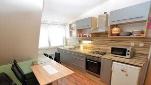 Una cocina compacta con encimera de madera, horno empotrado, microondas y refrigerador.