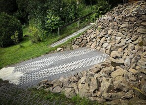 A stone pathway leading through a garden with a wooden fence and a stone wall. - Comfy Holiday Home near Forest in Medenec (Medenec)