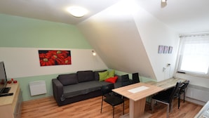 Un espacio habitable pequeño con un sofá, una mesa de comedor y un radiador.
