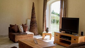 Un salon comprenant un canapé, une table basse, un téléviseur et un grand arbre décoratif.