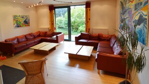 A modern living room with leather sofas, wooden coffee tables, and a large window with curtains. - Scenic Villa Near Lake View (Waimes)
