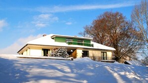 A two-story house with a snow-covered roof and a green balcony. - Scenic Villa Near Lake View (Waimes)