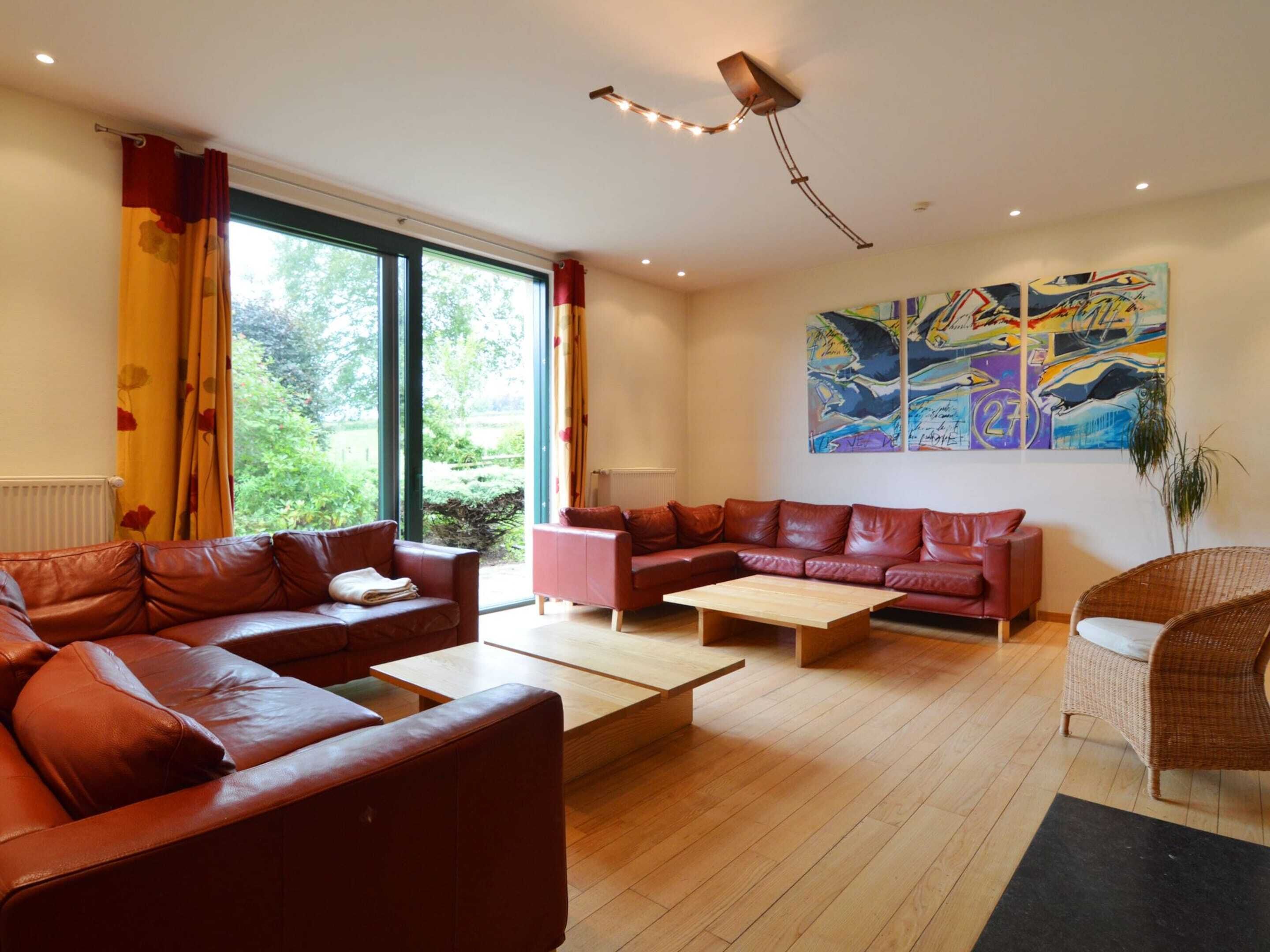 A modern living room with leather sofas, a wooden coffee table, and a large window with curtains.