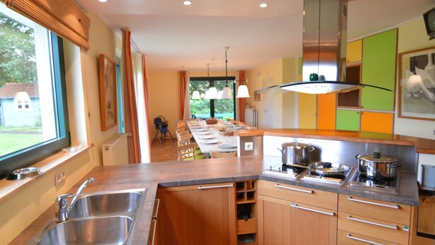 A modern kitchen with a large island, stainless steel sink, and wooden cabinets. - Scenic Villa Near Lake View (Waimes)