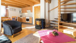 A cozy living room with a fireplace, a television, and a dining area with a table and chairs. - Beautiful Holiday Home in Weinebene With Sauna (Frantschach-Sankt Gertraud)