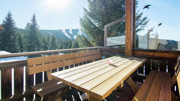 A wooden deck with a table and benches, overlooking a snowy landscape with trees and a clear sky. - Beautiful Holiday Home in Weinebene With Sauna (Frantschach-Sankt Gertraud)