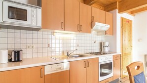A kitchen with wooden cabinets, a microwave, a coffee maker, and a dishwasher. - Beautiful Holiday Home in Weinebene With Sauna (Frantschach-Sankt Gertraud)