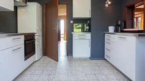 A compact kitchen with white cabinets, a stainless steel range hood, and a clock on the wall. - Hillside Stay Near Coo Fall (Stavelot)