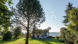 A white house with a lawn and trees in the foreground, and a body of water in the background. - Hillside Stay Near Coo Fall (Stavelot)