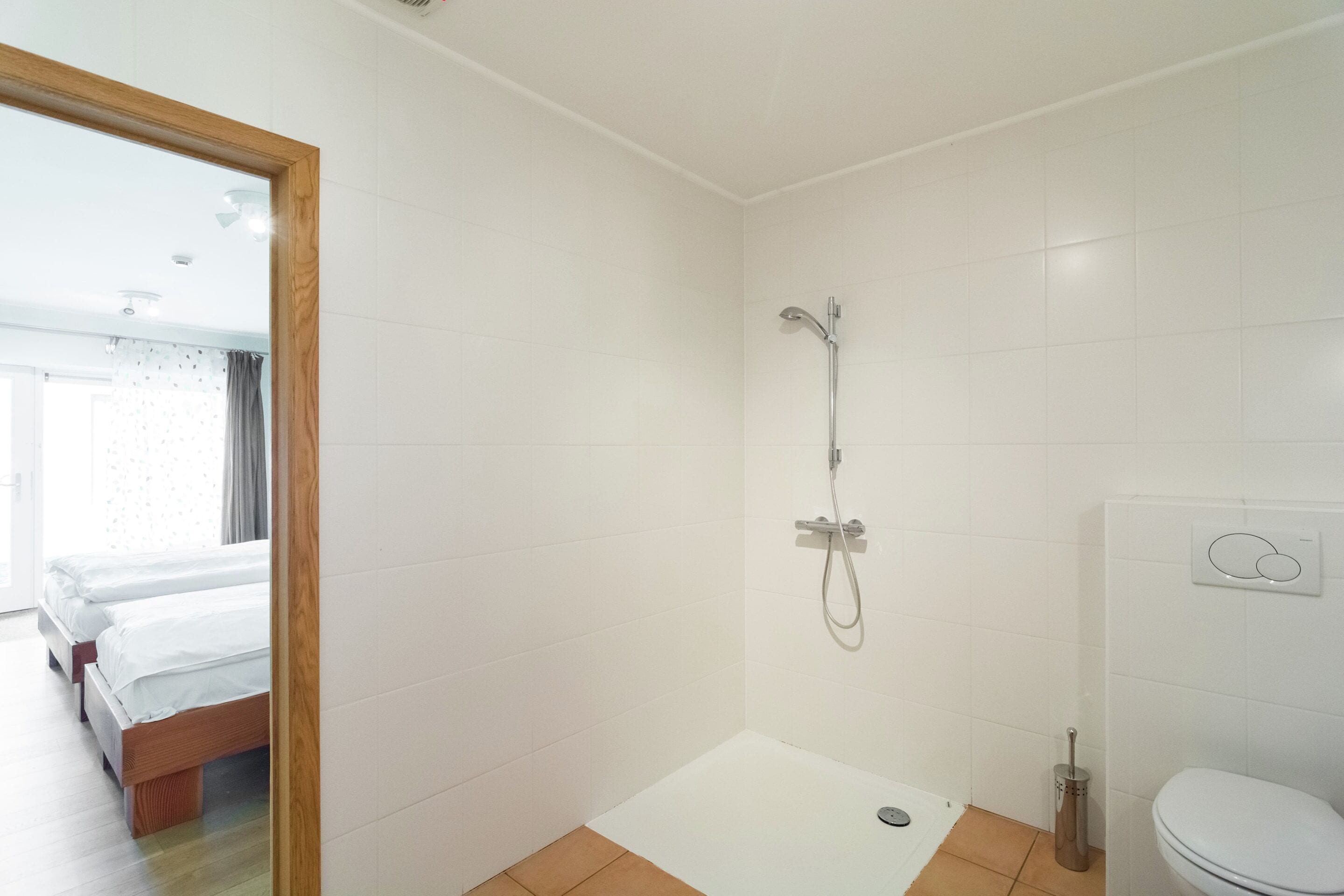 Un baño con ducha, inodoro y una cama en la habitación contigua.