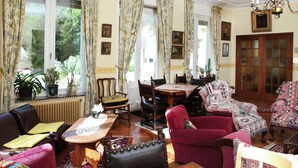 A traditional living room with a dining area, featuring classic furniture, large windows with floral curtains, and a chandelier. - Mansion in Ruiselede Doomkerke (Ruiselede)