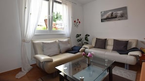 A living room with two sofas, a glass coffee table, and a window with curtains. - Geraeumige Ferienwohnung an der Ostsee (Carinerland)