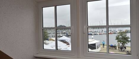 A room with a view of a marina through large windows, a radiator below, and a basket on the radiator.