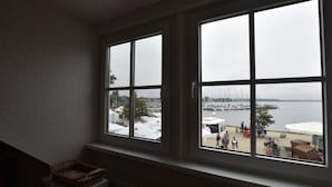Een kamer met een groot raam met uitzicht op een jachthaven met boten en parasols.