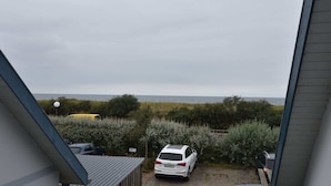 Overzicht van een parkeerplaats met een witte auto vlakbij een gebouw, omringd door groen en een waterpartij op de achtergrond.