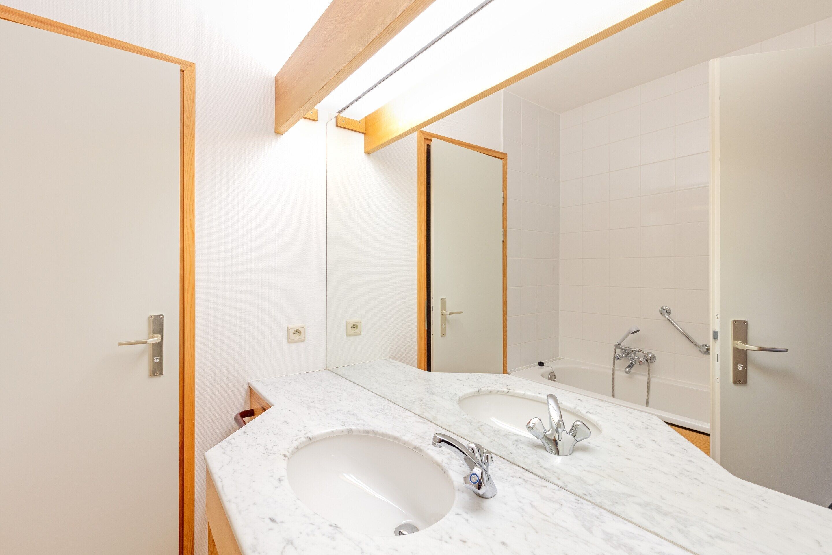A bathroom with two sinks, a large mirror, and a shower area.