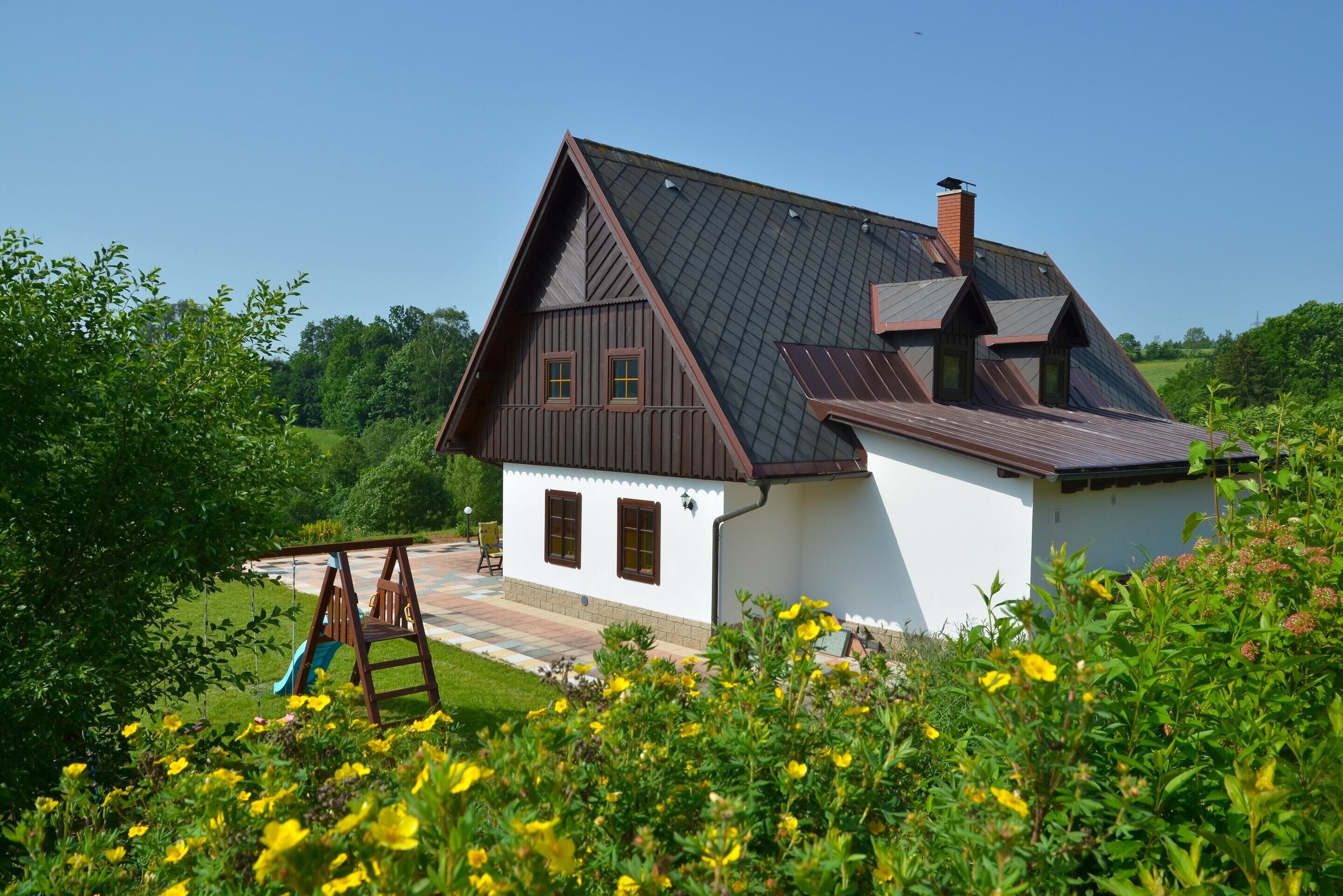 Une maison avec un toit en pente, une cheminée et un petit porche.