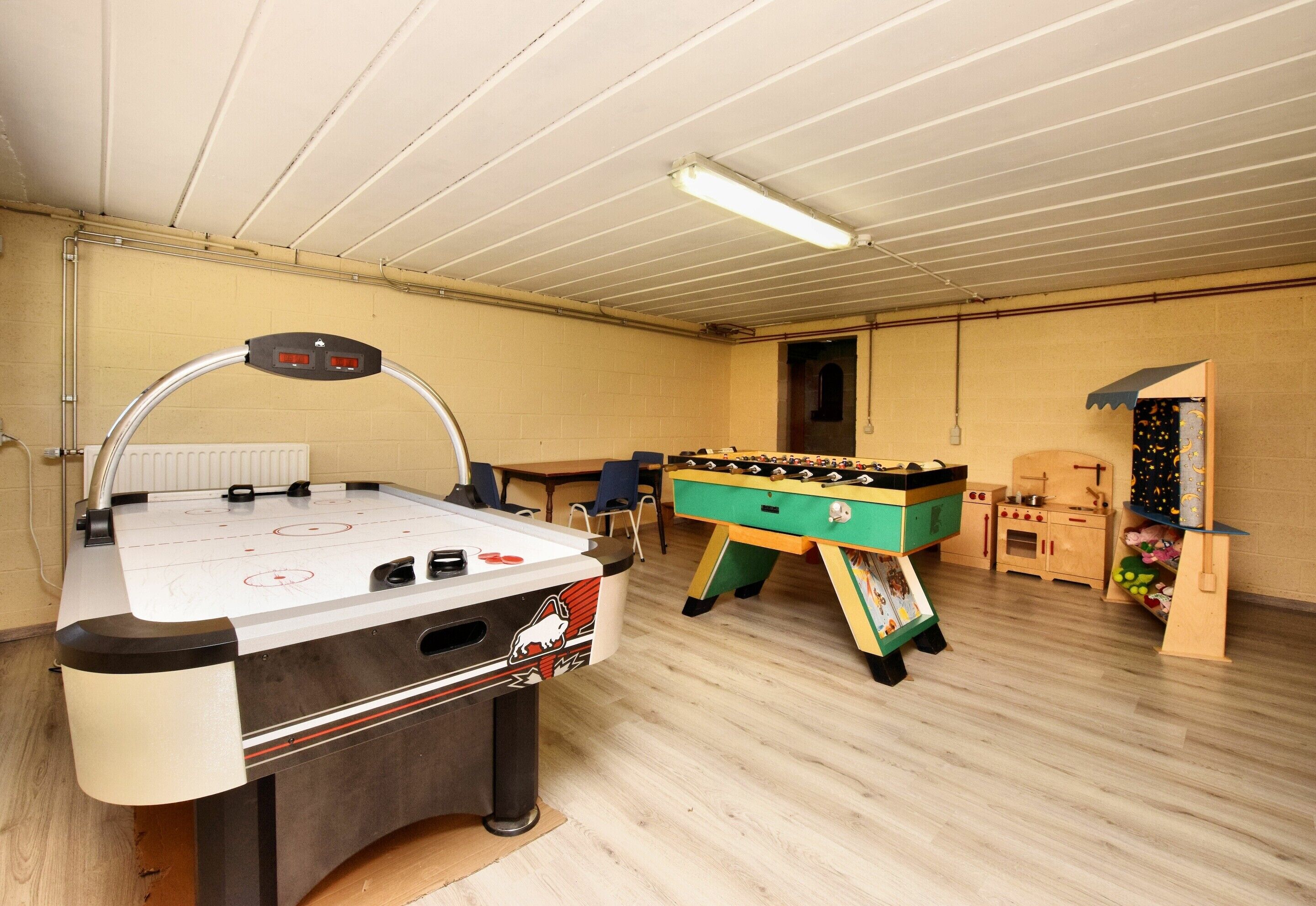 A room with a foosball table, a pool table, and a foosball table with a colorful design.