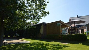 A modern building with a wooden facade and a covered outdoor seating area. - Child Friendly Holiday Home in Waimes with Sauna & Hot Tub (Waimes)