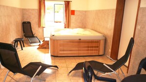 A room with a wooden hot tub, two black chairs, a small stool, and a window with curtains. - Child Friendly Holiday Home in Waimes with Sauna & Hot Tub (Waimes)