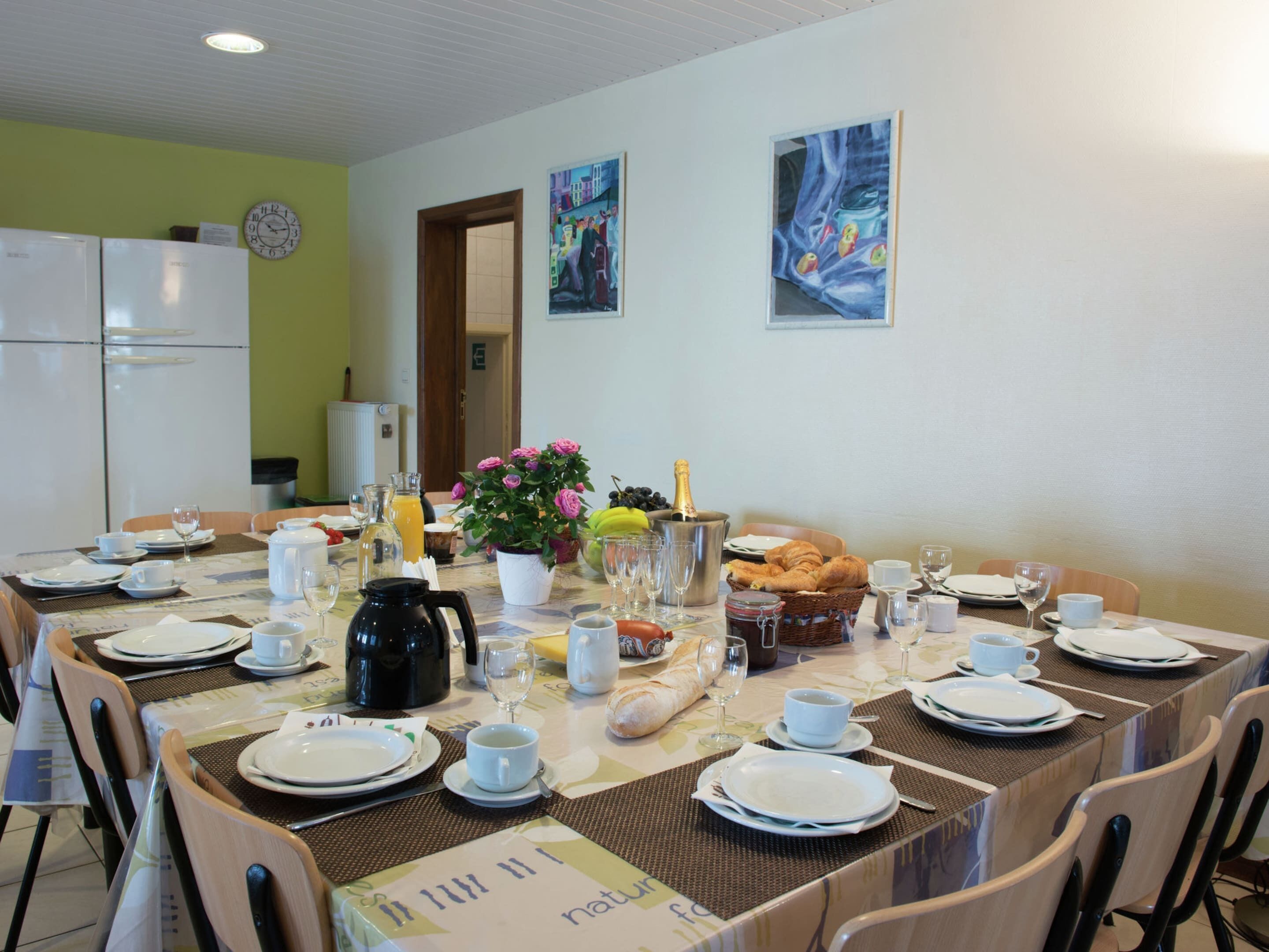 Un coin repas avec une table mise pour le petit-déjeuner, comprenant des assiettes, des tasses et une variété d’aliments.