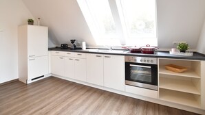 Een moderne keuken met witte kasten, een inbouwoven, een koffiezetapparaat en een raam boven de spoelbak.
