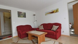 Un salon avec un canapé rouge, une table basse en bois et un tapis à motifs.