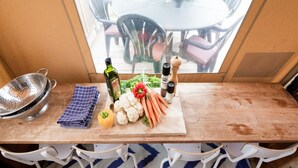 A wooden table with a colander, a bottle of olive oil, fresh vegetables, and pepper shakers. - Cozy Tent Lodge in Pittem With Veranda,barbecue (Pittem)