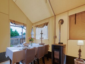 Een eethoek met een tafel gedekt voor twee personen, een decoratieve vaas met bloemen en een houtkachel.