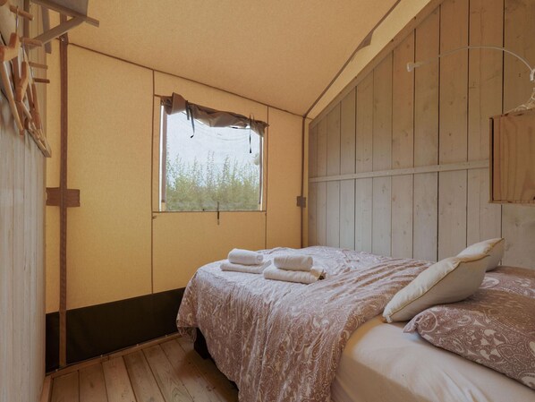A bedroom with a bed, a window, and wooden walls.