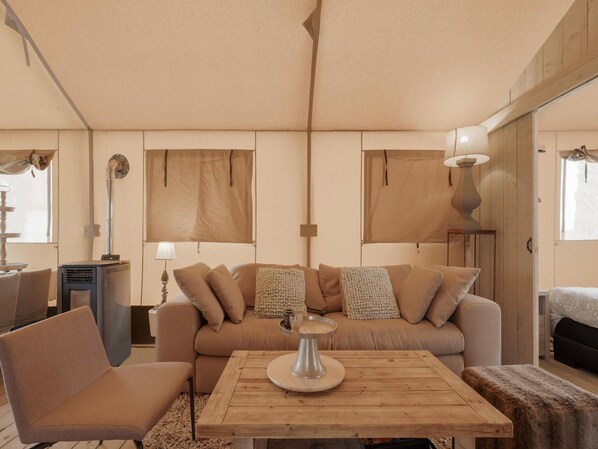 A cozy living room with a sofa, a coffee table, and a lamp. - Cozy Tent Lodge in Pittem With Veranda,barbecue (Pittem)