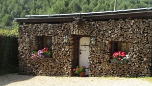 A stone building with a gravel driveway, two flower boxes with pink flowers, and a door with a window. - Lovely Spot With Plenty of Outdoor Space (Sainte-Ode)