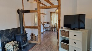 Ein rustikaler Innenraum mit freiliegenden Holzbalken, einem Kamin, einem Fernseher und einem Essbereich.