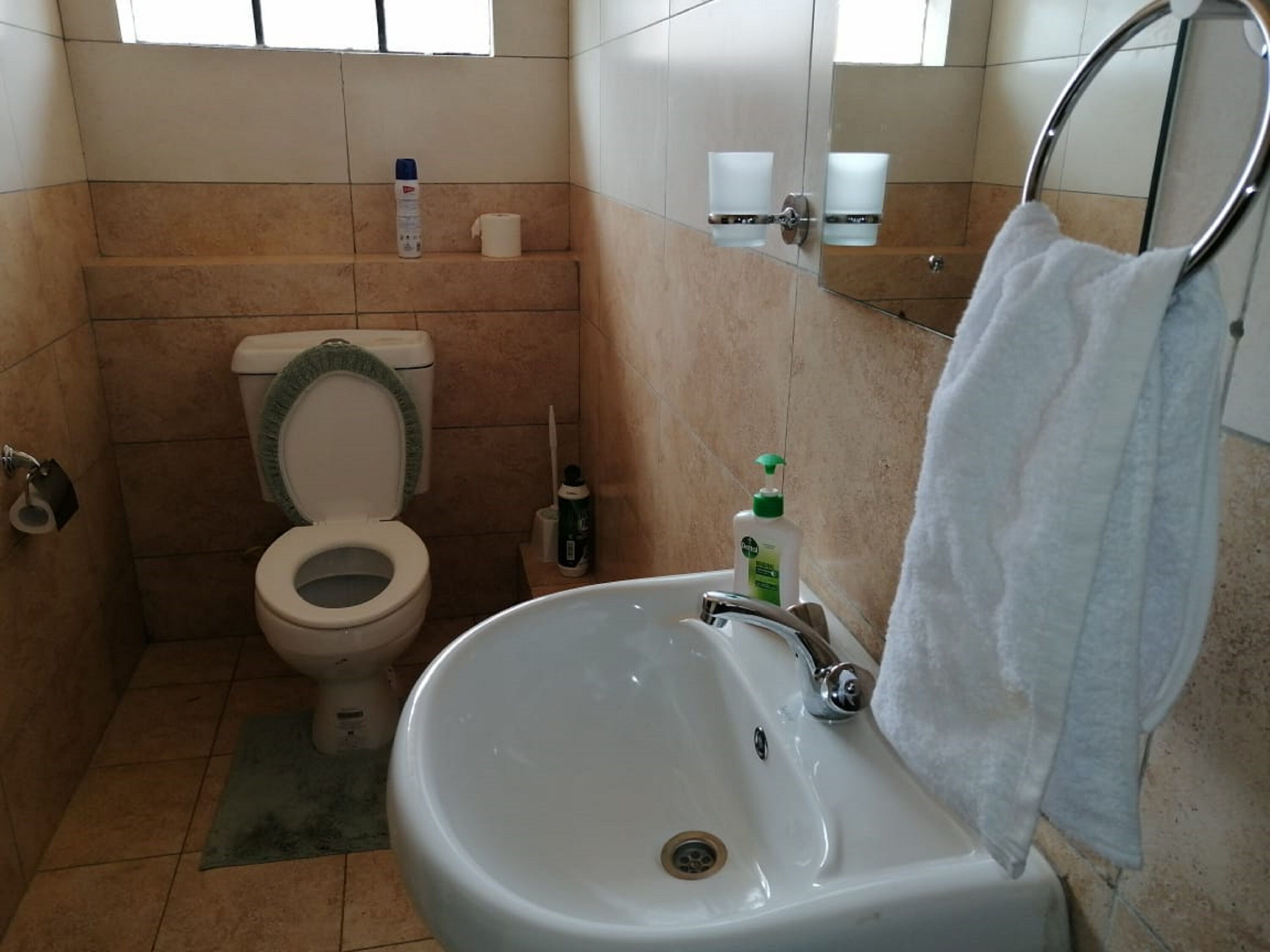 A bathroom with a toilet, sink, and a towel rack.