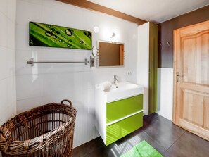 A modern bathroom with a white sink, green cabinet, and a wicker basket. - Ardennes View Apartment- Petit Wilogne (Houffalize)