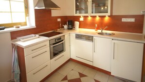 A compact kitchen with white cabinets, a built-in oven, a sink, and a window.