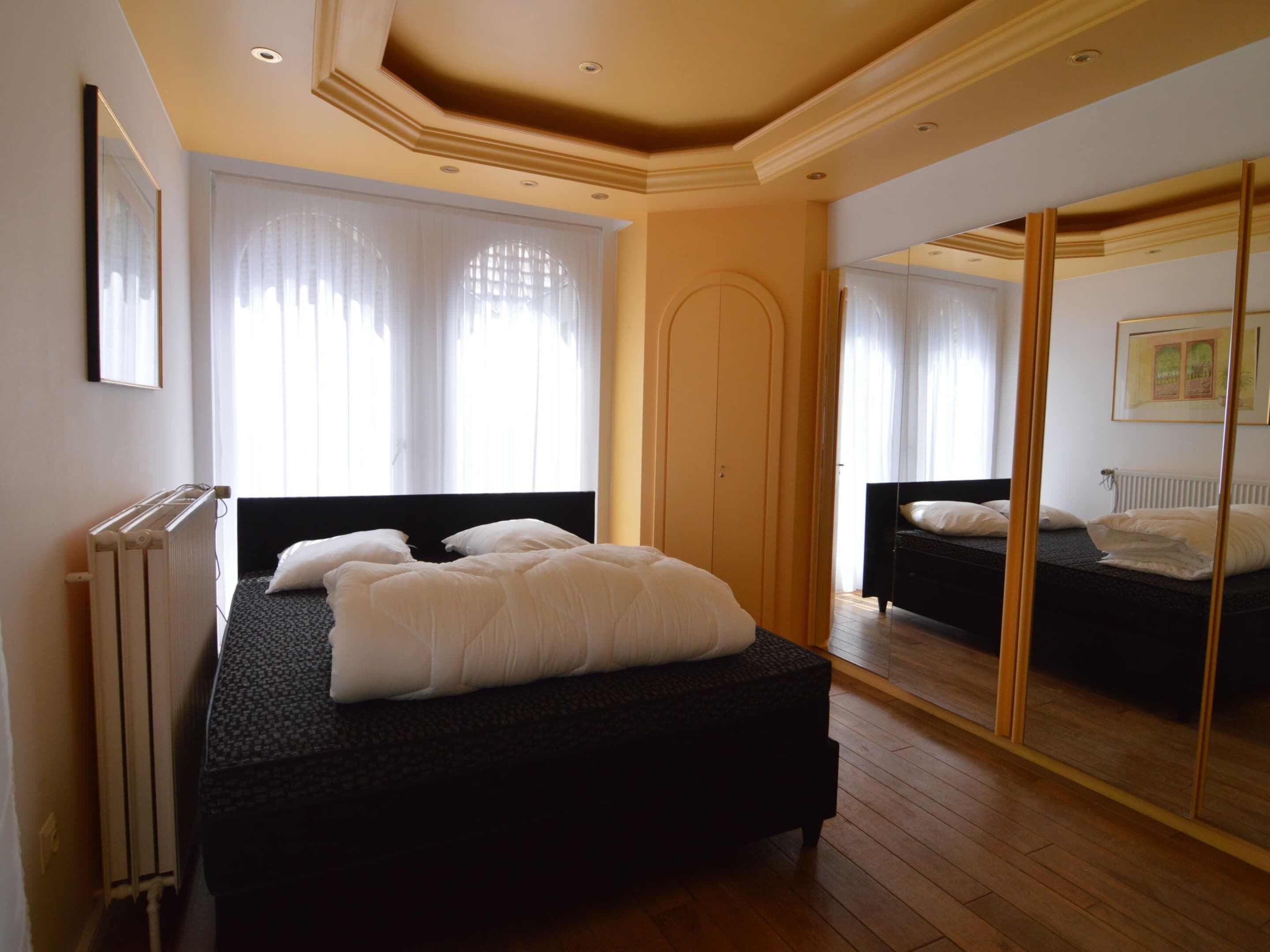 A bedroom with a large bed, a radiator, and a mirror on the wall.