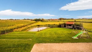 Un paysage rural avec un champ d’herbe, une petite construction en bois et une balançoire.