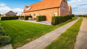 Un bâtiment en briques avec un toit en pente, une allée pavée et une pelouse bien entretenue.