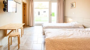 Une chambre d’hôtel avec deux lits, un bureau, une chaise, une télévision et une vue sur l’extérieur.