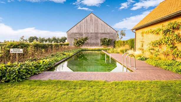 Un cadre extérieur paisible avec une piscine, une grange en bois et un bâtiment en briques.