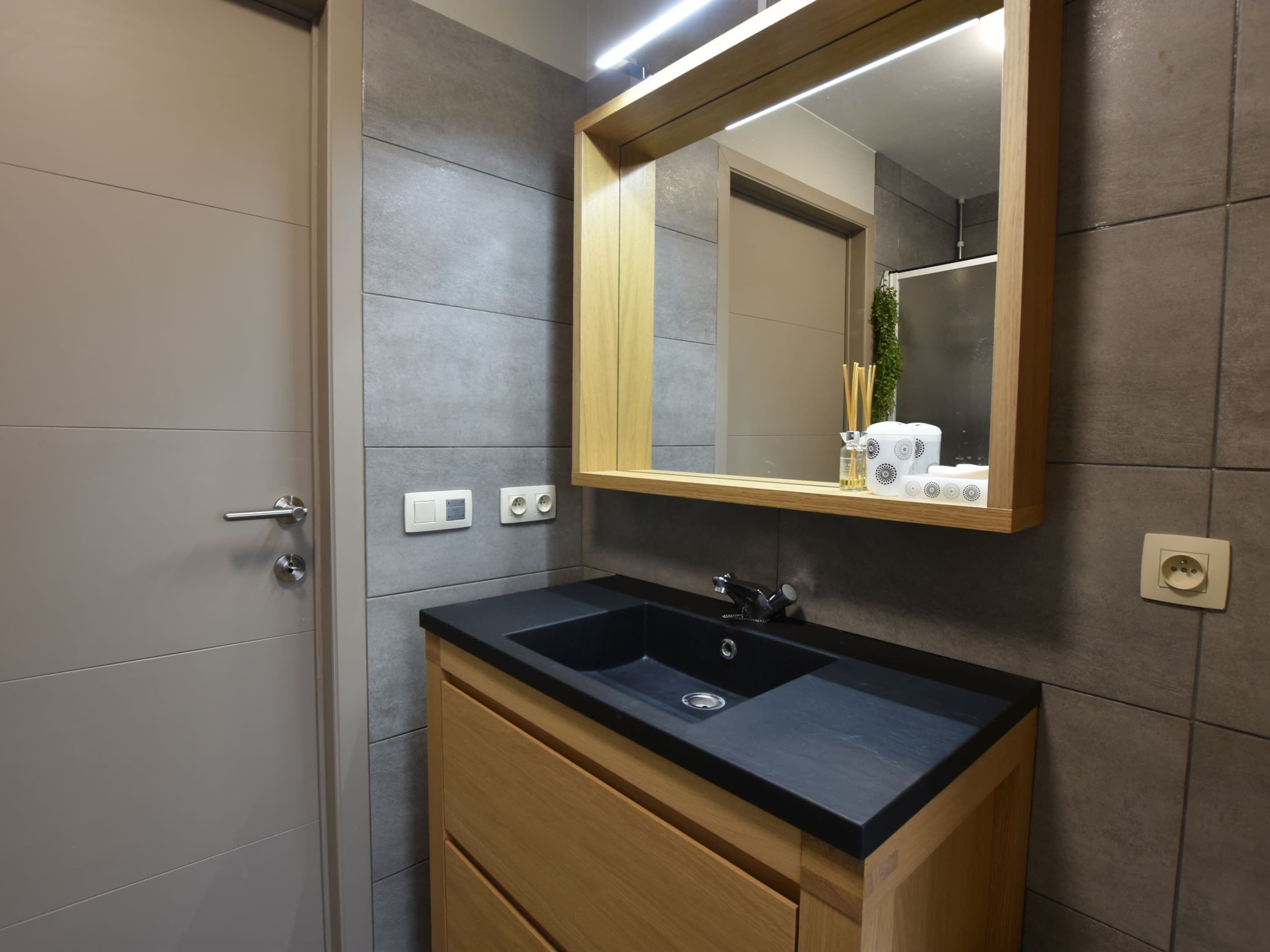 A modern bathroom with a black sink, wooden vanity, and a mirror.
