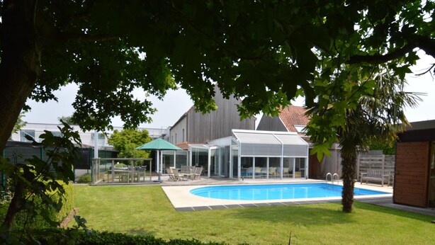 A backyard with a swimming pool, a covered patio area, and a lawn. - Beautiful Villa for Groups With Swimming Pool, Sauna and Wifi (Zottegem)