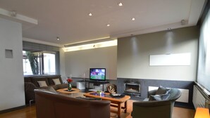 A modern living room with a fireplace, a television, and comfortable seating. - Beautiful Villa for Groups With Swimming Pool, Sauna and Wifi (Zottegem)