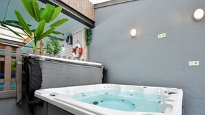 A spa area with a hot tub, a wooden deck, and a potted plant. - Luxury Pool Villa in Goesnes (Ohey)