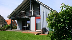 A modern building with a sloped roof, a covered entrance, and a small outdoor seating area. - Holiday House on the Island of Poel (Insel Poel)