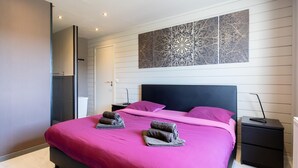 A modern bedroom with a large bed, two pillows, and a decorative wall piece.