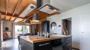 A modern kitchen with a central island, black cabinetry, and pendant lighting.