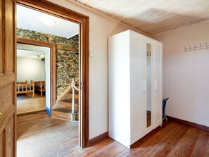 Une pièce avec un plancher en bois, une armoire blanche et un mur en pierre.